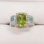 9ct gold ring featuring single large peridot with two tourmaline gems either side surrounded by diamonds