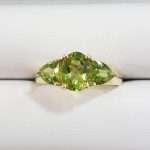9ct gold ring featuring large oval faceted peridot with two triangular shaped peridot gems either side