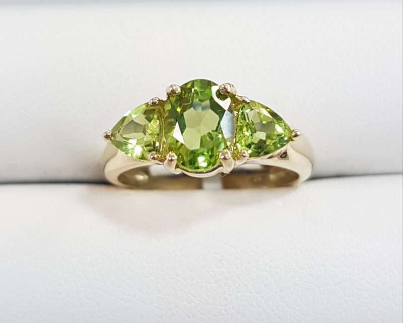 9ct gold ring featuring large oval faceted peridot with two triangular shaped peridot gems either side