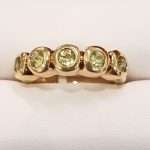 9ct gold ring featuring 5 round faceted peridot gemstones in gold pod design