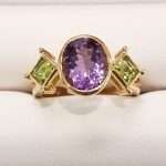 9ct gold ring featuring large faceted oval amethyst with two faceted square peridot gems either side
