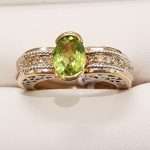 9ct gold ring featuring large faceted oval peridot and decorative band encrusted with diamonds